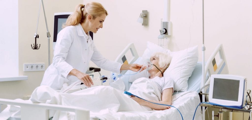 Female physician adjusting respiratory support while standing next to patient